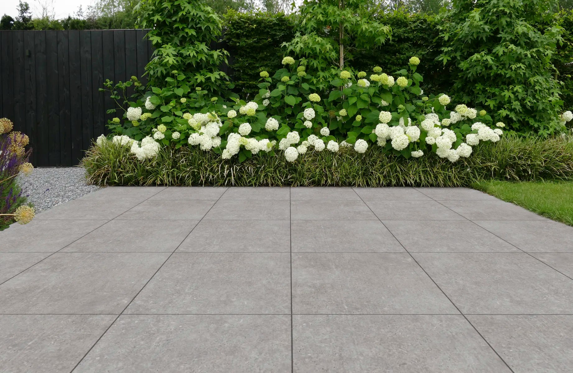 Aangelegd keramisch terras met grijze tegels en witte hortensia's